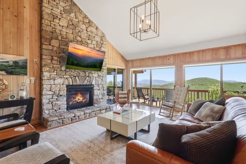 The living room is the heart of the home — anchored by a beautiful stone fireplace and flowing seamlessly onto the deck, where breathtaking mountain views set the scene for unforgettable evenings.