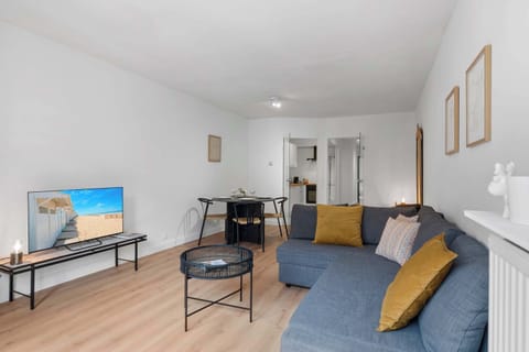 Comfortable living room with a blue sofa, smart TV and bright windows — unwind after a day exploring Knokke and its nearby beach.