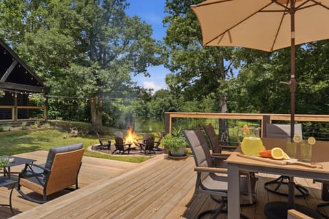 Scenic waterfront deck with fire pit, dining area, and serene wooded views