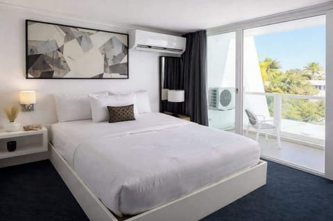 A bright and relaxing bedroom with a plush king bed, modern décor, and a private balcony overlooking lush tropical greenery — perfect for slow mornings and peaceful nights.