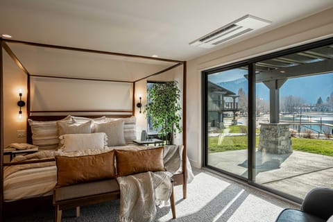 Wake up to stunning lakeside views from a luxurious master bedroom complete with an elegant canopy bed and direct patio access.