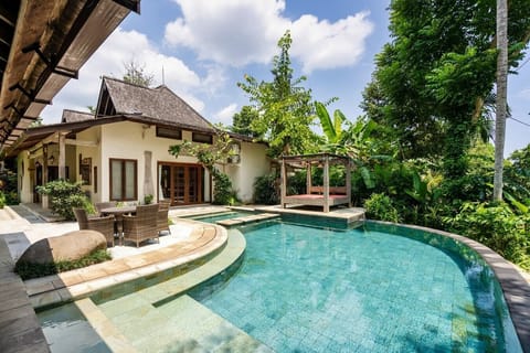 A beautiful villa set in a lush tropical garden, featuring a stunning free-form pool surrounded by greenery. The villa’s architecture blends traditional and modern elements, offering a luxurious and tranquil retreat.