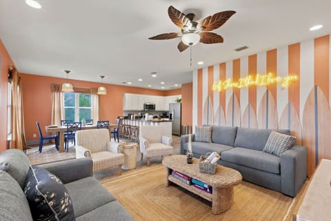 Bright coastal-style living space with open kitchen and fun neon accent