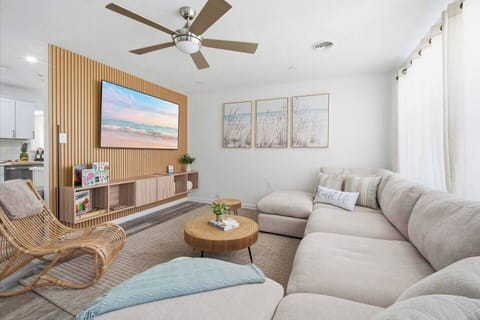 Gather with family in this bright, coastal-inspired living room featuring a large sectional, Smart TV, cozy seating, board games, and beachy décor. The perfect place to relax after a day at the beach or spend quality time together.