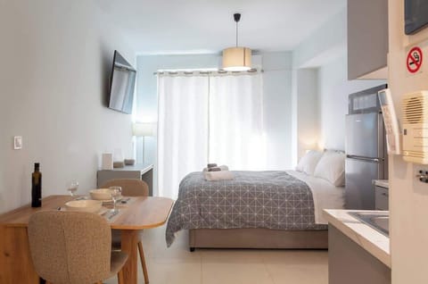 The main living space feels bright and calm, with the bed placed beside the window and dining area.