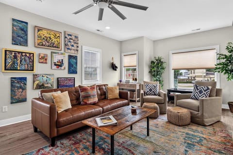 Living Room — Unit 2: Leather sectional, gallery wall, and the kind of golden-hour light that makes every seat the best seat.