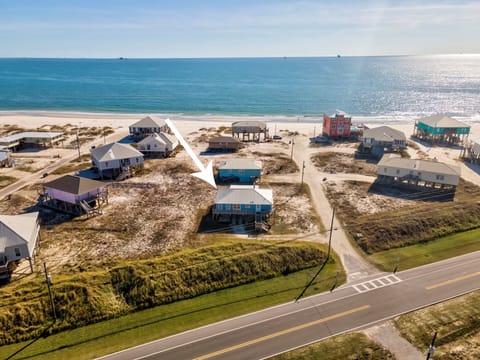 Aerial view of beachfront vacation homes along the coast with pristine white sand and the Gulf of Mexico as a backdrop, creating an idyllic arrival setting.