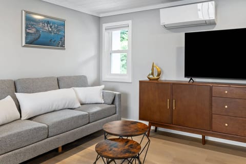 Living area corner with sofa, large flatscreen TV, mini-split HVAC, and natural light from the marina window.
