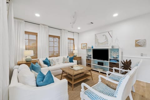 Living room with white slipcovered sofas, blue patterned armchairs, woven coffee table, and natural fiber rug.