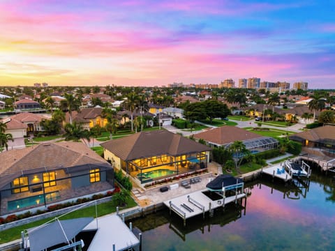 Breathtaking twilight aerial view capturing the glowing property amidst the scenic waterfront neighborhood.