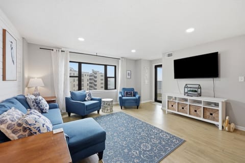 Unwind in your bright living space with cozy blue seating, a large TV, and a lovely city view—perfect for relaxing after your daily adventures.