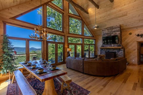 The Great Room is the heart of Rested Traveler — dramatic vaulted ceilings, exposed log beams, a gorgeous stone fireplace, and a stunning wall of windows framing endless long-range mountain views.