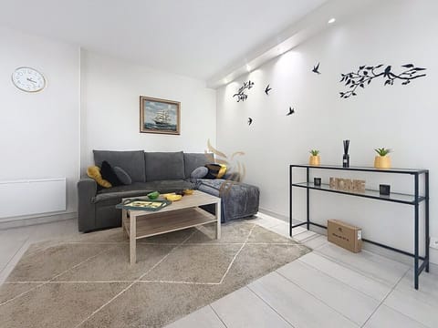 Posez-vous sur le canapé gris, la couverture et les coussins vous invitent à une soirée tranquille. La table basse en bois et l`éclairage encastré créent une atmosphère cocooning rythmée par les stickers d`oiseaux.