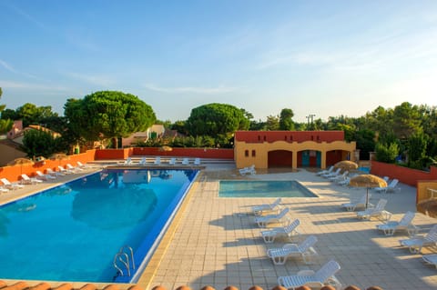 The outdoor pool open from May to September, ringed by sun loungers and framed by ochre walls and pines.