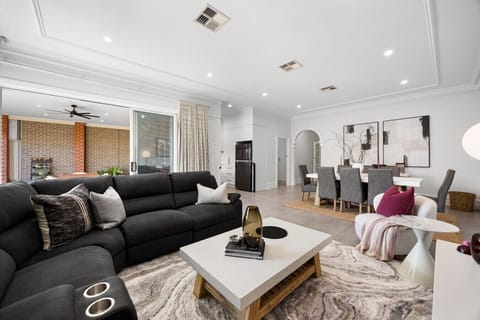 The open-plan living and dining area blends contemporary furnishings with elegant heritage character, offering a seven-seater lounge, an eight-seat dining table, and generous space to unwind together.