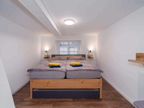 Bright private double room with a comfortable bed, window, fresh towels, and simple practical furnishings.
