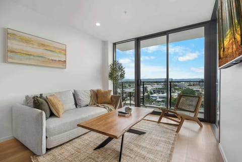Open-plan living area with smart TV, lounge chair and floor-to-ceiling windows.