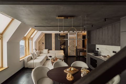 Na pierwszym poziomie znajduje się przestronny salon z rozkładaną sofą, który stanowi wygodną strefę relaksu. Dodatkowym atutem tej części apartamentu jest rzutnik umieszczony nad sofą oraz ekran wysuwany z sufitu.