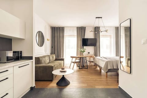 Główna przestrzeń apartamentu łączy strefę wypoczynkową, sypialnianą oraz jadalnianą. Znajduje się tu wygodne łóżko małżeńskie, sprzyjające pełnemu relaksowi po dniu zwiedzania lub pracy, a także komfortowa rozkładana sofa.