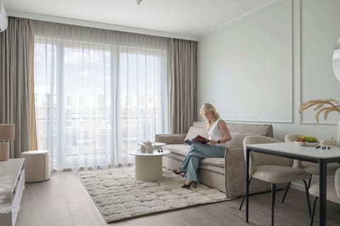 Jasny salon z wygodną sofą i Smart TV zapewnia idealne warunki do relaksu. Klimatyzacja gwarantuje komfort przez cały rok, a duże okna i eleganckie dodatki tworzą przytulną, nowoczesną przestrzeń.