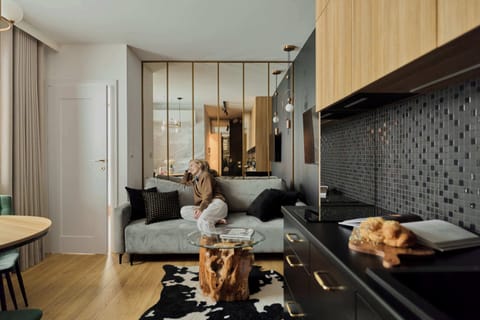 W salonie znajduje się rozkładana sofa oraz telewizor z kanałami kablowymi i Smart TV. Stylowe oświetlenie i dodatki nadają wnętrzu przytulny, nowoczesny charakter.