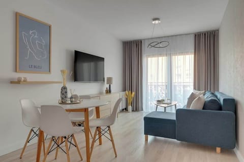 W salonie znajduje się wygodna, rozkładana sofa z funkcją spania, która zapewnia dodatkowe miejsce noclegowe, a także telewizor z funkcją Smart TV, idealny do wieczornego relaksu.