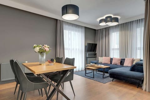 Przytulny salon oferuje wygodną, rozkładaną sofę idealną do relaksu po dniu zwiedzania. Ustawiony przed nią stolik kawowy tworzy wygodną strefę wypoczynku, a telewizor naprzeciwko zapewnia rozrywkę o każdej porze dnia.