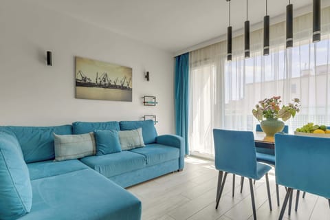 Centralnym punktem mieszkania jest przestronny salon z dużą, rozkładaną sofą ustawioną naprzeciwko telewizora, która zapewnia komfortowy wypoczynek po całym dniu. 