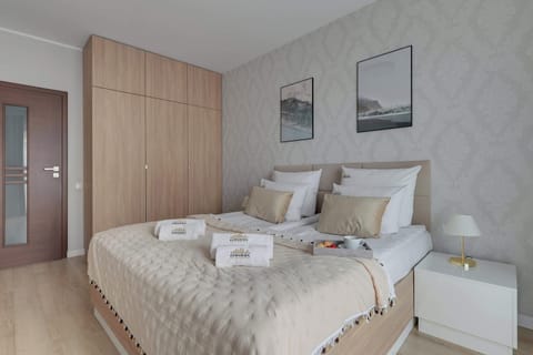 Elegancka sypialnia w jasnych, stonowanych kolorach zapewnia komfortowy wypoczynek. Wygodne łóżko, duża szafa oraz subtelne dodatki tworzą przytulne i harmonijne wnętrze sprzyjające relaksowi.