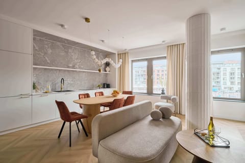 Salon został urządzony w jasnej, eleganckiej stylistyce z wykorzystaniem miękkich tkanin, drewna i dekoracyjnych elementów ściennych. Znajduje się tu wygodna rozkładana sofa.