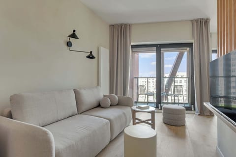 Główną część apartamentu stanowi otwarta przestrzeń łącząca salon i sypialnię. Znajduje się tu wygodne łóżko małżeńskie, sofa oraz telewizor z funkcją Smart TV i kanałami kablowymi.