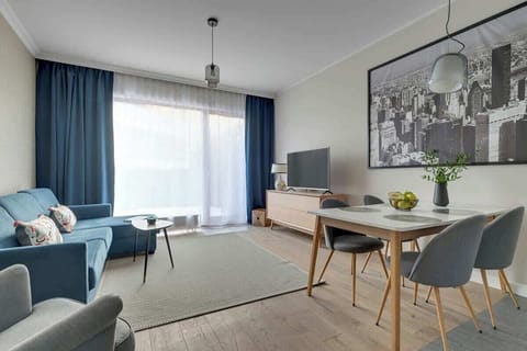 Przytulny salon to jasna, funkcjonalna przestrzeń idealna do relaksu. Znajduje się tu wygodna, rozkładana sofa stanowiąca dodatkowe miejsce do spania oraz fotel tworzący komfortowy kącik wypoczynkowy. Naprzeciw stoi telewizor z dostępem do kanałów TV