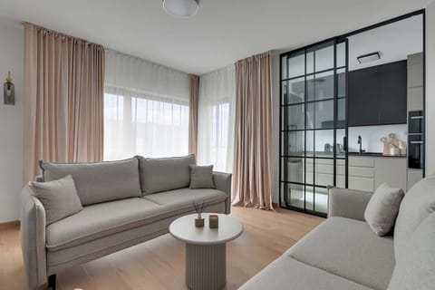 Centralnym punktem jest przestronny salon wyposażony w dwie rozkładane sofy, tworzące idealne miejsce do relaksu, a naprzeciw nich znajduje się telewizor z dostępem do kanałów i funkcją Smart TV. 