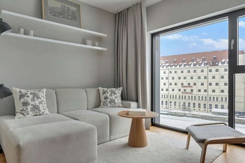 Jasny salon wyposażony jest w wygodną sofę oraz telewizor z kanałami kablowymi i Smart TV, idealny na wieczorny relaks. Duże przeszklenia zapewniają piękny widok na rzekę, który dodaje wnętrzu lekkości i wyjątkowego charakteru.