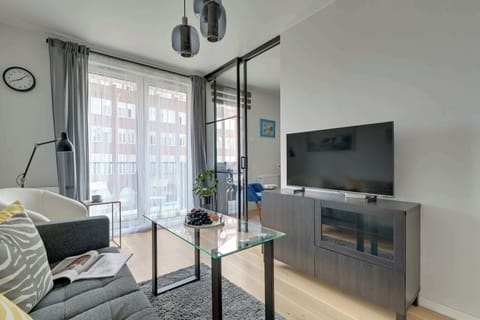Przytulny salon z wygodną sofą, fotelem i stolikiem kawowym tworzy idealną przestrzeń do relaksu. Duże okna zapewniają dużo światła, a Smart TV i stylowe dodatki podnoszą komfort codziennego wypoczynku.