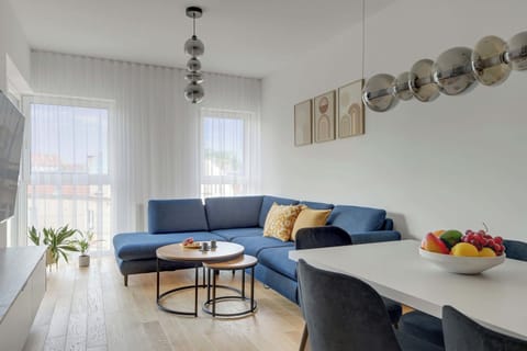 Nowoczesny salon z dużymi przeszkleniami zachwyca jasnym wnętrzem, designerskim oświetleniem i eleganckim wykończeniem. Komfortowa strefa wypoczynku połączona z aneksem kuchennym tworzy idealną przestrzeń do relaksu i wspólnego spędzania czasu.