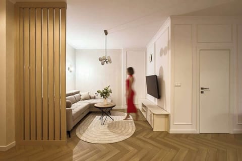 Przytulny salon z rozkładaną sofą to idealne miejsce do wspólnego wypoczynku – wygodny narożnik, designerski stolik i duży telewizor tworzą domowy klimat. Jasne ściany, miękkie tekstylia i eleganckie dodatki sprzyjają relaksowi po dniu pełnym wrażeń.