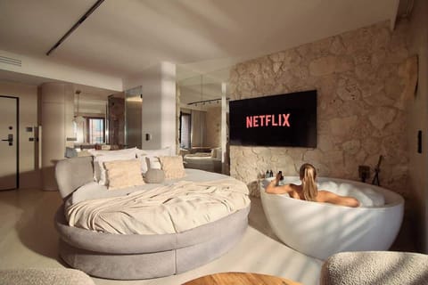 Centralnym punktem apartamentu jest duże, okrągłe łóżko małżeńskie. Wyjątkowym elementem jest wolnostojąca wanna z funkcją jacuzzi, umieszczona w części wypoczynkowej – idealna do relaksu przy filmie na telewizorze Smart TV z dostępem do Netflixa.