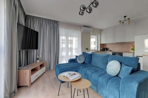 W klimatyzowanym salonie znajduje się duża, rozkładana sofa, telewizor z dostępem do kanałów kablowych oraz funkcją Smart TV. Przestrzeń uzupełnia stół z krzesłami, przy którym można wygodnie zjeść posiłek lub spędzić czas przy wspólnych rozmowach.
