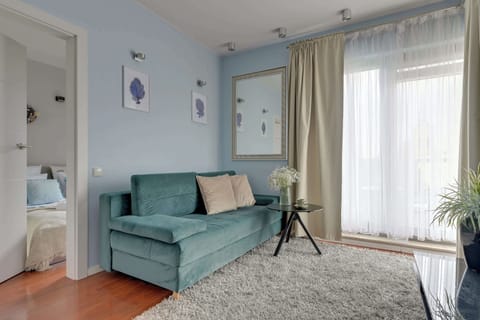 Elegancki i jasny salon został urządzony z dbałością o komfort i estetykę wnętrza. Znajduje się tu wygodna rozkładana sofa usytuowana naprzeciw telewizora z kanałami kablowymi oraz funkcją Smart TV.