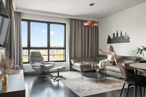 Znajduje się tu rozkładana sofa, która zapewnia wygodne miejsce do relaksu w ciągu dnia i dodatkową przestrzeń do spania. Obok ustawiono komfortowy fotel z podnóżkiem, tworzący idealny kącik do odpoczynku z książką lub kawą.