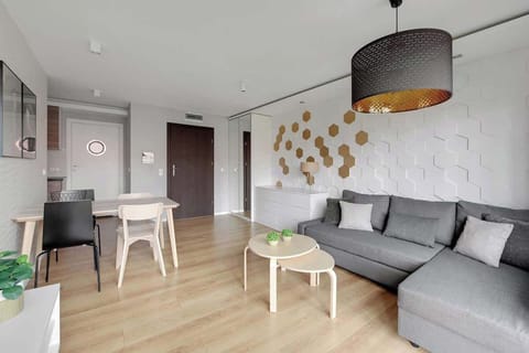 Stylowy, jasny salon urządzono w nowoczesnym stylu. Znajduje się tu rozkładana sofa, stolik kawowy, fotel oraz telewizor naprzeciw strefy wypoczynkowej. Dodatkowym atutem są pojemna szafa i komoda.