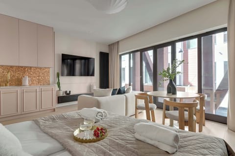 Główną część apartamentu stanowi otwarta przestrzeń łącząca salon i sypialnię. Znajduje się tu wygodne łóżko małżeńskie, sofa oraz telewizor z funkcją Smart TV.
