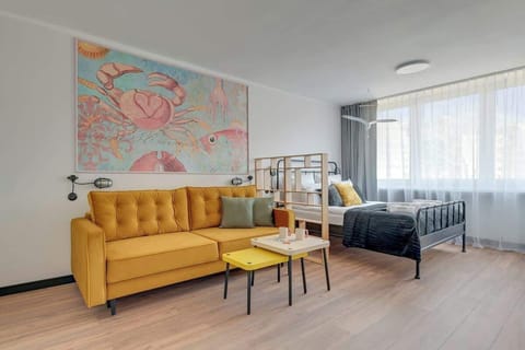 Salon łączy strefę wypoczynku i snu. Znajduje się tu rozkładana sofa, Smart TV, łóżko małżeńskie oraz szafa, dzięki czemu przestrzeń jest komfortowa i funkcjonalna.