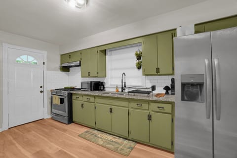 Bright kitchen with sage cabinets, full-size fridge, and gas stove