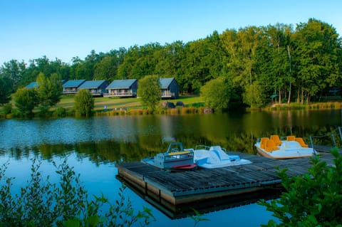 Pedal boats at the wooden dock, with three chalets nestled among the trees alongside the lake.