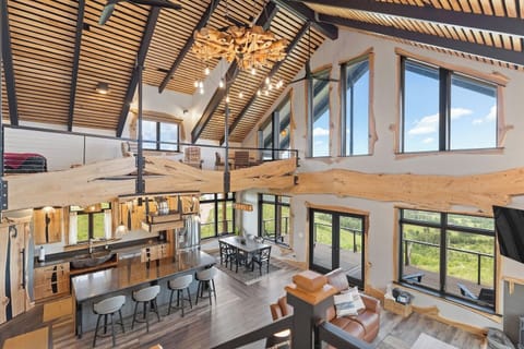 The Bald Doe features a stunning open-concept living space with soaring vaulted ceilings, expansive windows, and a spacious loft, all showcasing breathtaking mountain views.