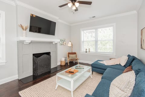 Bright & Airy Gathering Space – Relax in this sunlit living room featuring a Smart TV, modern fireplace, sleek décor, and cozy textures.