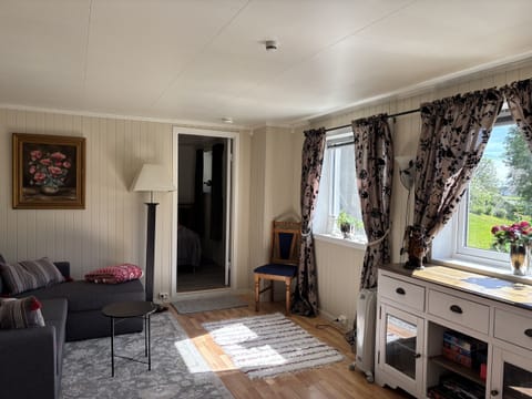 living room featuring a sofa, patterned curtains and warm home décor with wooden flooring
