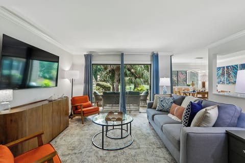 Unwind in your stylish living space featuring plush seating, modern accents, and direct access to your private patio overlooking lush tropical greenery.